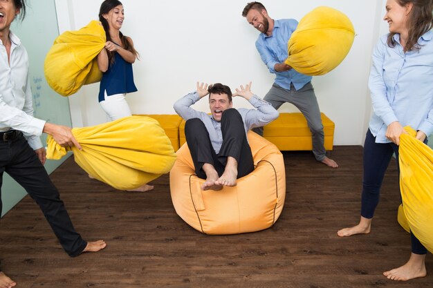 hombre gritando que es golpeado con almohadas de amigos