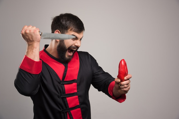 Hombre gritando tratando de cortar un pimiento rojo.