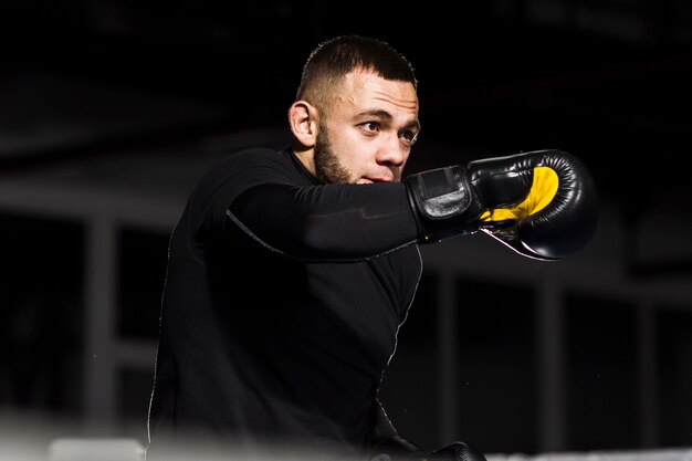 Hombre en guantes protectores posando mientras boxeo