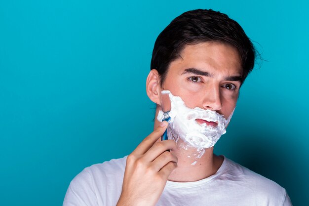 Hombre guapo afeitándose la barba