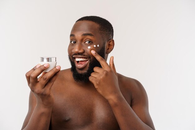 Hombre guapo africano aplicando crema en su rostro mans concepto de cuidado de la piel