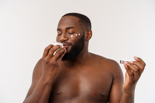 Hombre guapo africano aplicando crema en su rostro mans concepto de cuidado de la piel