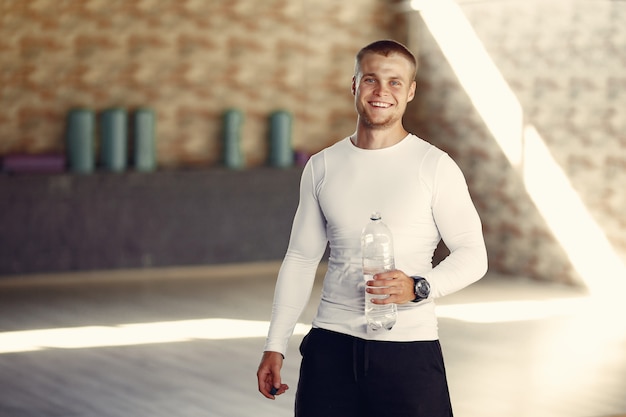 Hombre guapo agua potable en el gimnasio