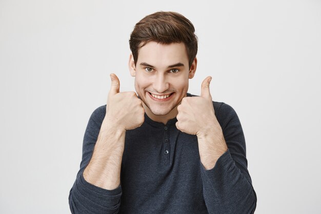 Hombre guapo y alegre emocionado mostrando el pulgar hacia arriba en aprobación