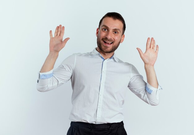 Hombre guapo alegre está parado con las manos levantadas aislado en la pared blanca