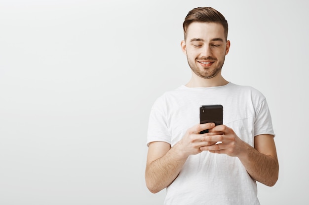 Hombre guapo con aplicación móvil. Guy mensajería con smartphone