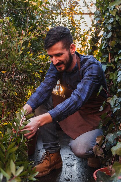 Hombre guapo atendiendo a las plantas