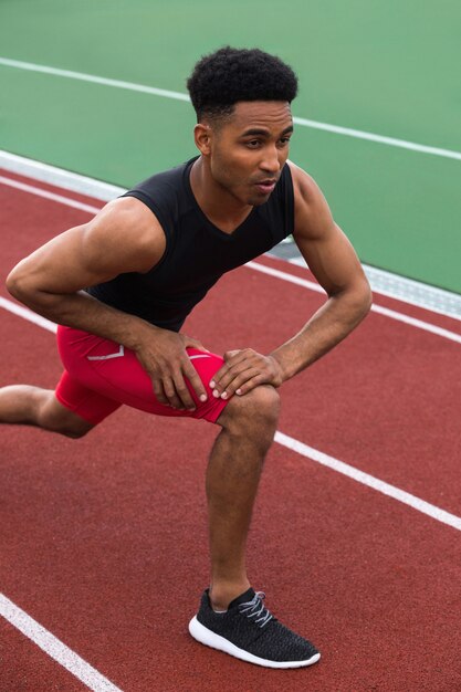 Hombre guapo atleta africano concentrado hacer ejercicios de estiramiento