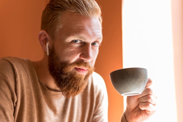 Foto gratuita hombre guapo con auriculares sosteniendo una taza de café