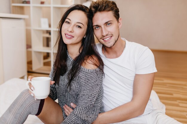 Hombre guapo con barba abrazando suavemente a la mujer europea mientras bebe café