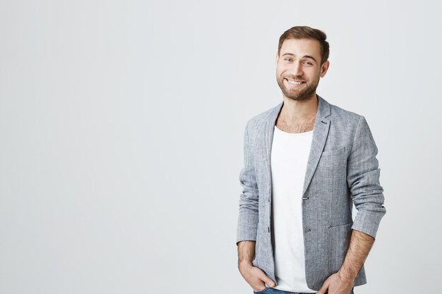 Hombre guapo con barba en chaqueta gris sonriendo cámara