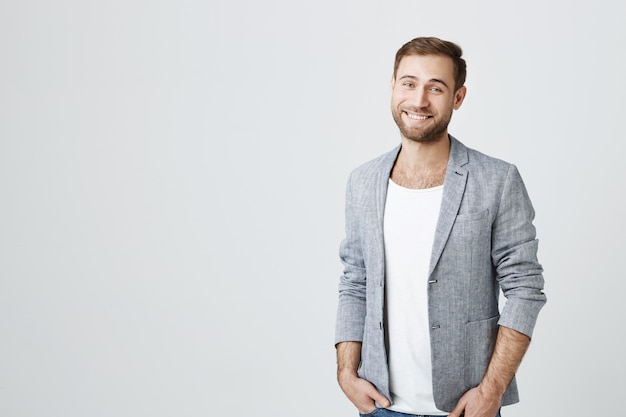 Hombre guapo con barba en chaqueta gris sonriendo cámara