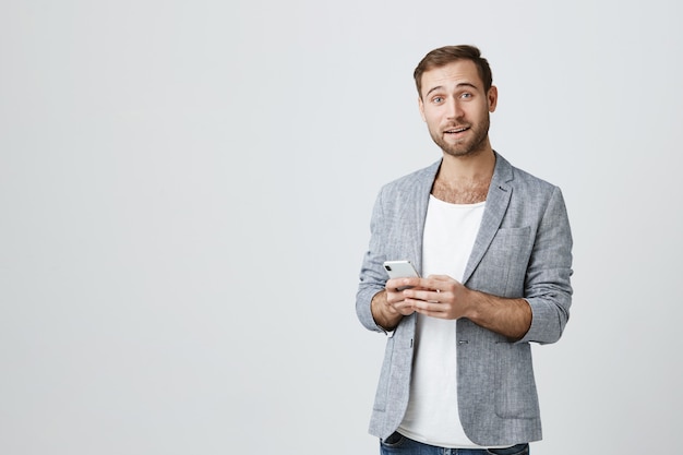 Hombre guapo con barba en la chaqueta mediante teléfono móvil