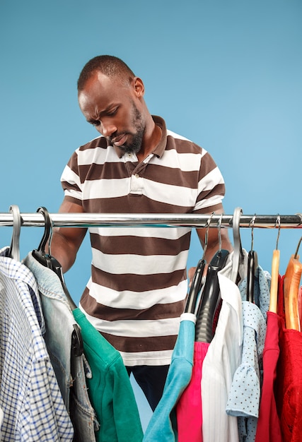 Foto gratuita hombre guapo con barba eligiendo camisa en una tienda