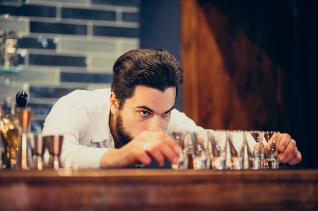 Hombre guapo barman haciendo bebidas y cócteles en un mostrador