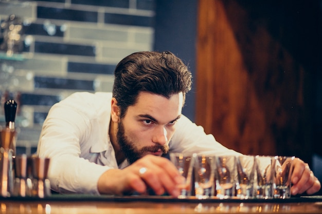 Hombre guapo barman haciendo bebidas y cócteles en un mostrador