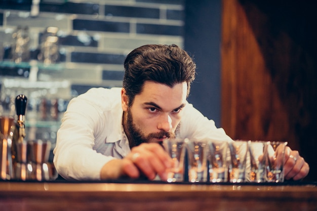 Hombre guapo barman haciendo bebidas y cócteles en un mostrador