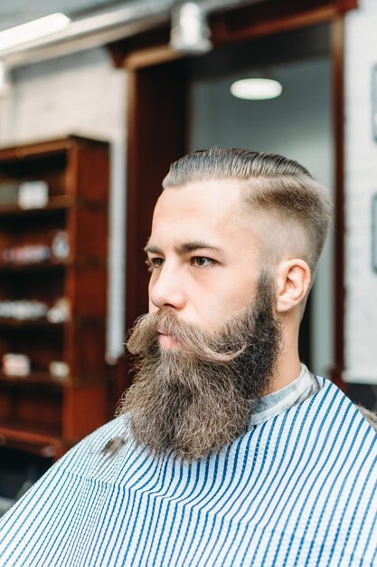 Hombre guapo con un bigote largo en la barbería después del corte de pelo