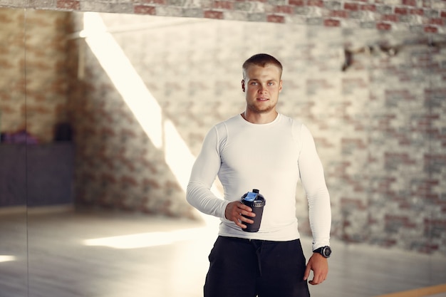 Hombre guapo con una botella de agua en un gimnasio