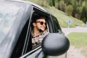 Foto gratuita hombre guapo de buen humor conduce un coche y disfruta del buen tiempo en vacaciones