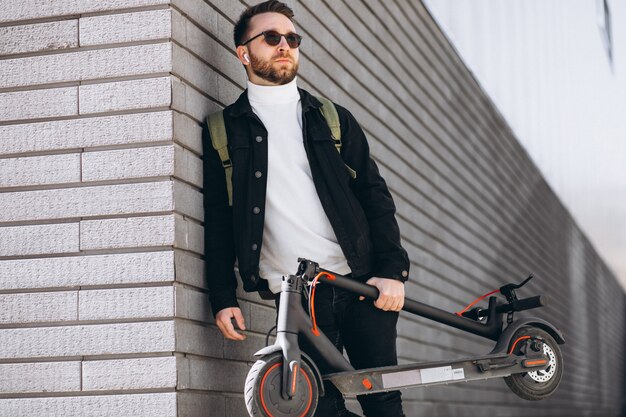 Hombre guapo cabalgando en la ciudad en scooter