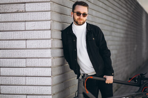 Hombre guapo cabalgando en la ciudad en scooter