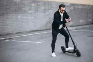 Foto gratuita hombre guapo cabalgando en la ciudad en scooter