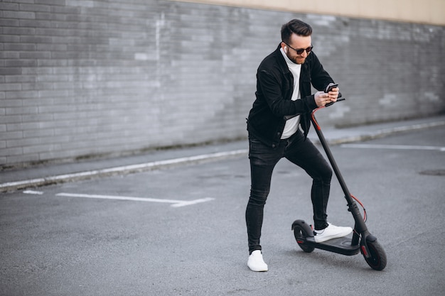 Hombre guapo cabalgando en la ciudad en scooter