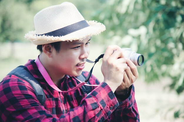 Hombre guapo con cámara en la naturaleza de viaje