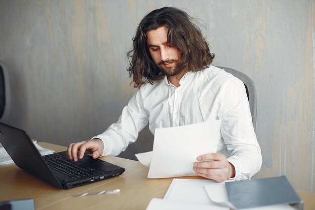 Hombre guapo con camisa blanca. Hombre de negocios trabajando en la oficina. Chico con una computadora portátil.