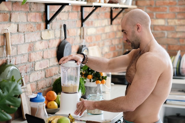 Hombre guapo, sin camisa en la cocina