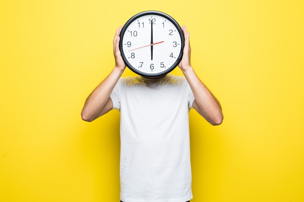 Hombre guapo con camiseta blanca y gafas transparentes sostiene un gran reloj en lugar de su cabeza