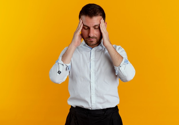 Foto gratuita hombre guapo cansado sostiene la cabeza mirando hacia abajo aislado en la pared naranja