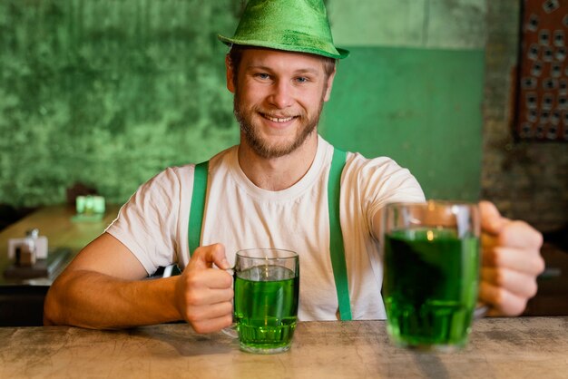 Hombre guapo celebrando st. día de patricio con bebidas en el bar.