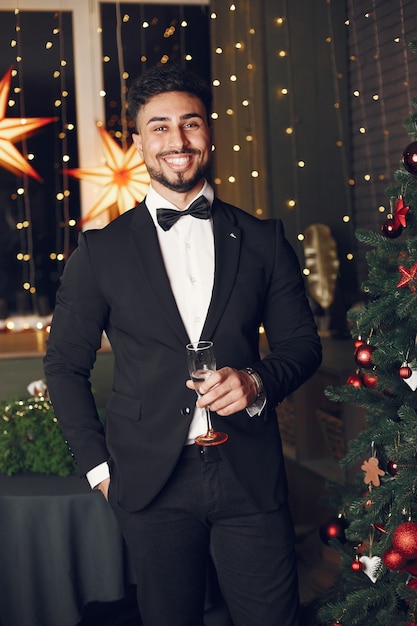 Hombre guapo cerca del árbol de Navidad. Gentelman con traje negro.