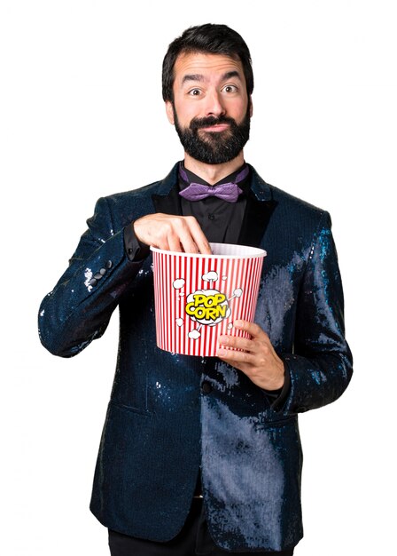 Hombre guapo con chaqueta de lentejuelas comiendo palomitas