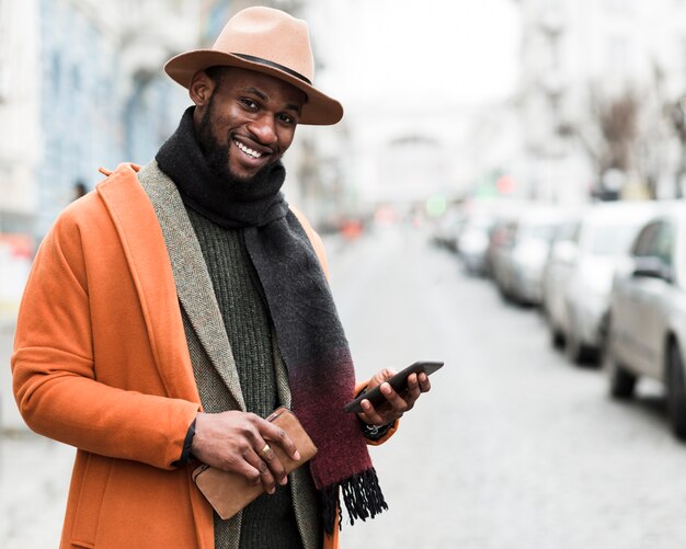 Hombre guapo en chaqueta naranja sosteniendo su teléfono