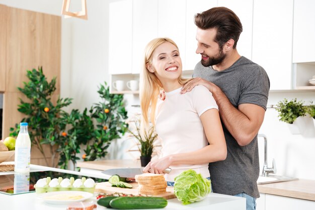 Hombre guapo cocinando con su joven novia en casa