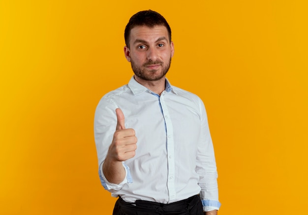 Hombre guapo complacido pulgares arriba aislado en la pared naranja