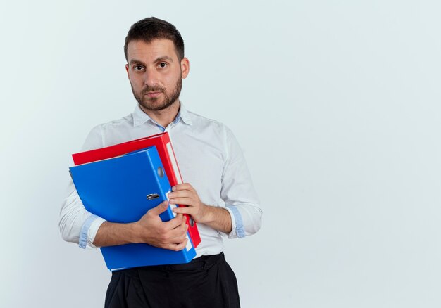 Hombre guapo confiado tiene carpetas de archivos aisladas en la pared blanca