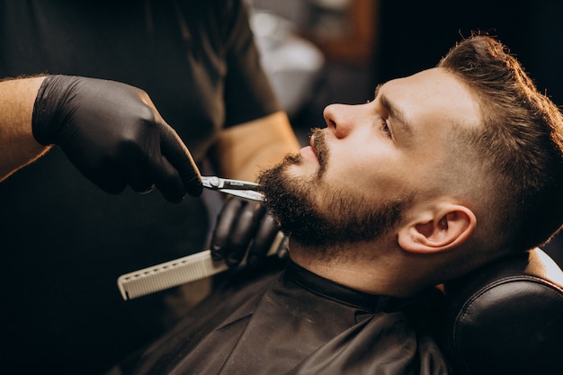 Hombre guapo cortando barba en un salón de peluquería