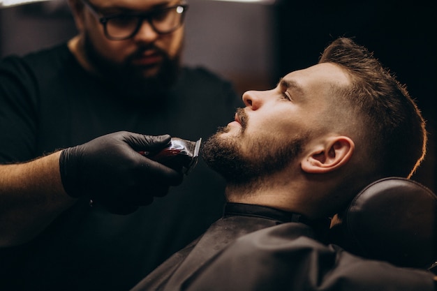 Hombre guapo cortando barba en un salón de peluquería