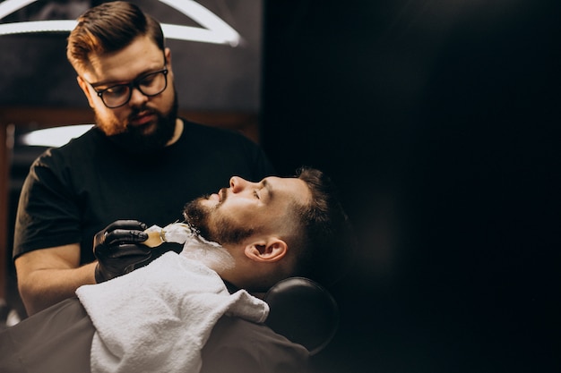 Hombre guapo cortando barba en un salón de peluquería