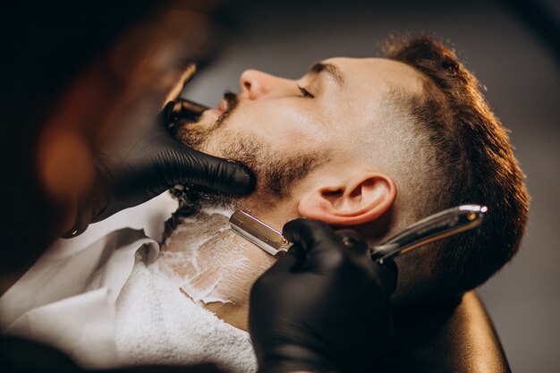 Hombre guapo cortando barba en un salón de peluquería