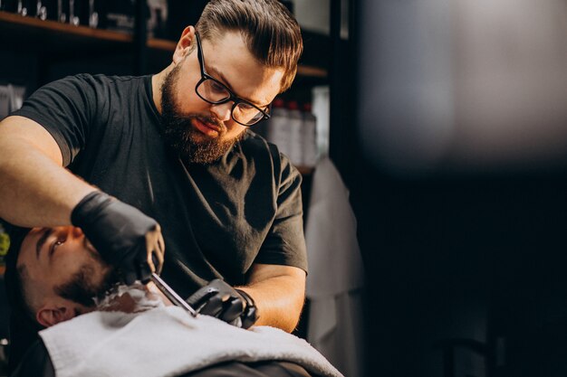 Hombre guapo cortando barba en un salón de peluquería