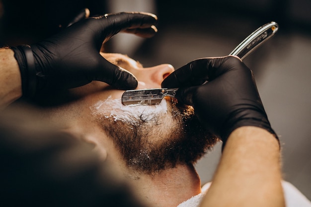 Hombre guapo cortando barba en un salón de peluquería