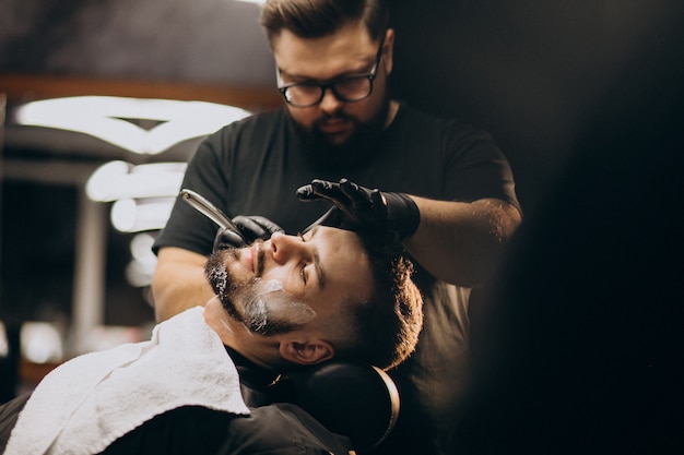 Hombre guapo cortando barba en un salón de peluquería