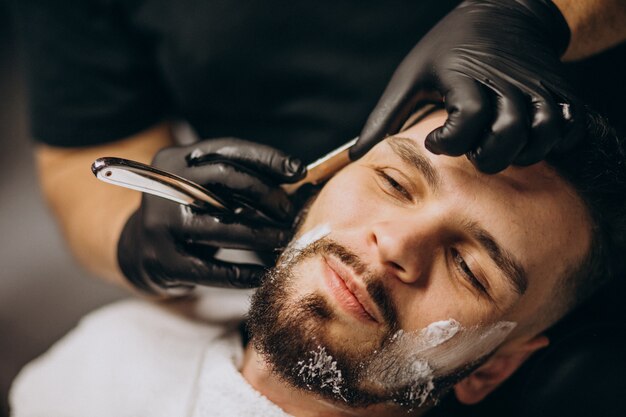 Hombre guapo cortando barba en un salón de peluquería