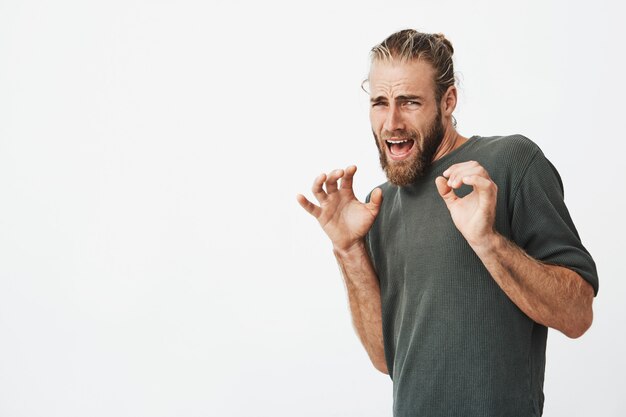 Hombre guapo con elegante cabello y barba gritando con expresión asustada