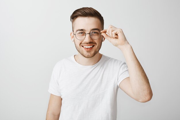 Hombre guapo elegante en gafas escuchando música con auriculares inalámbricos